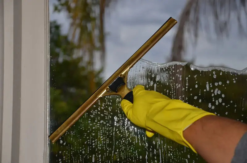 Hand mit gelbem Handschuh zieht eine Glasscheibe mit dem Abzieher ab
